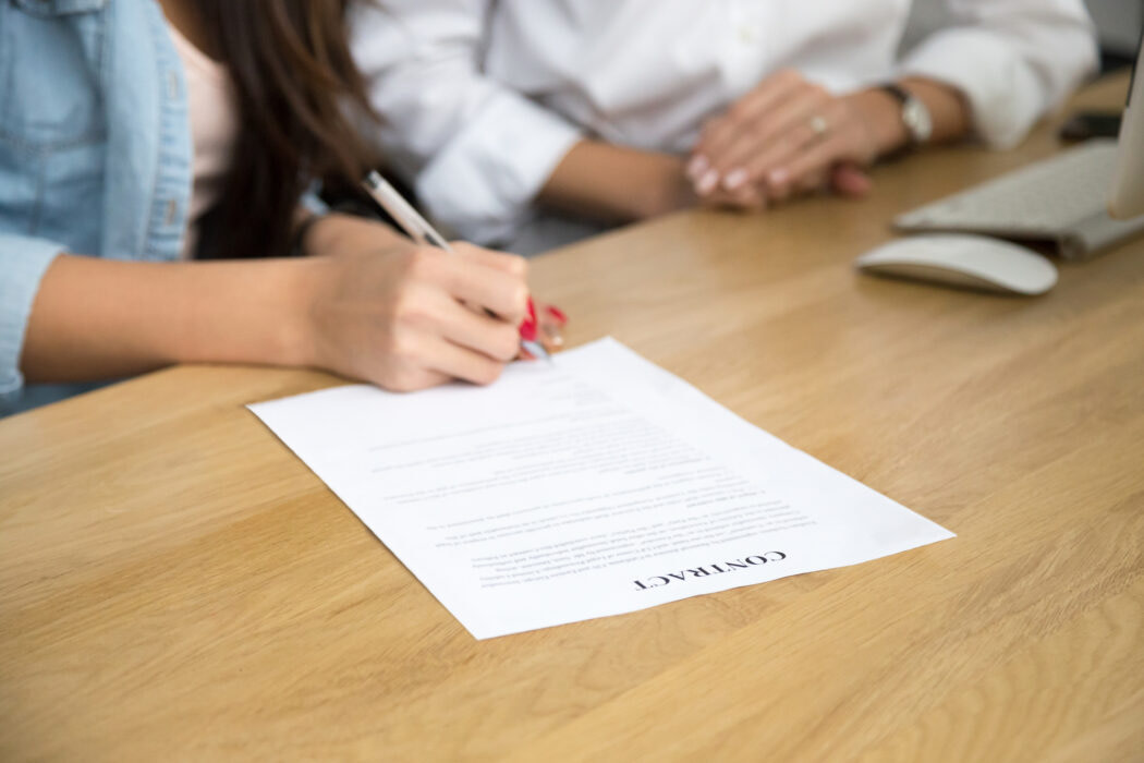 Woman signing contract, female hand putting written signature on document